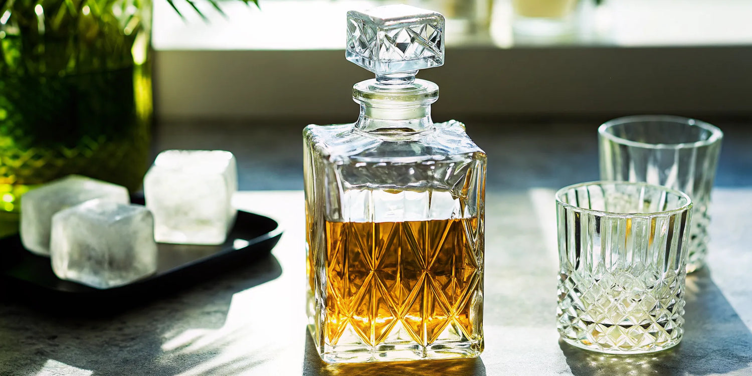 A decanter of cristalino tequila for sale with two glasses and ice.