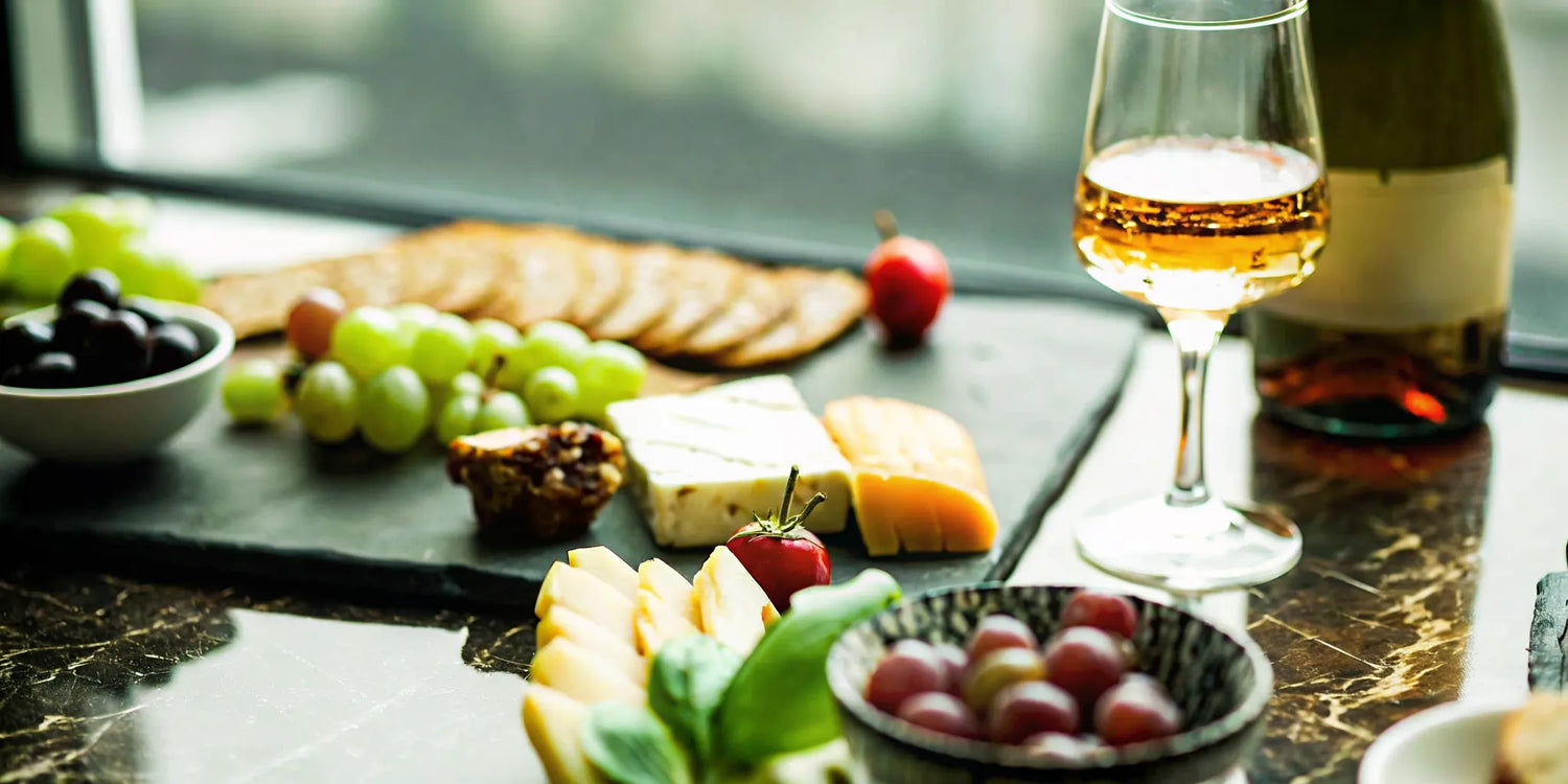 Elegant table setting with tequila bottles, glasses, and gourmet pairing dishes including cheese, chocolate, and steak